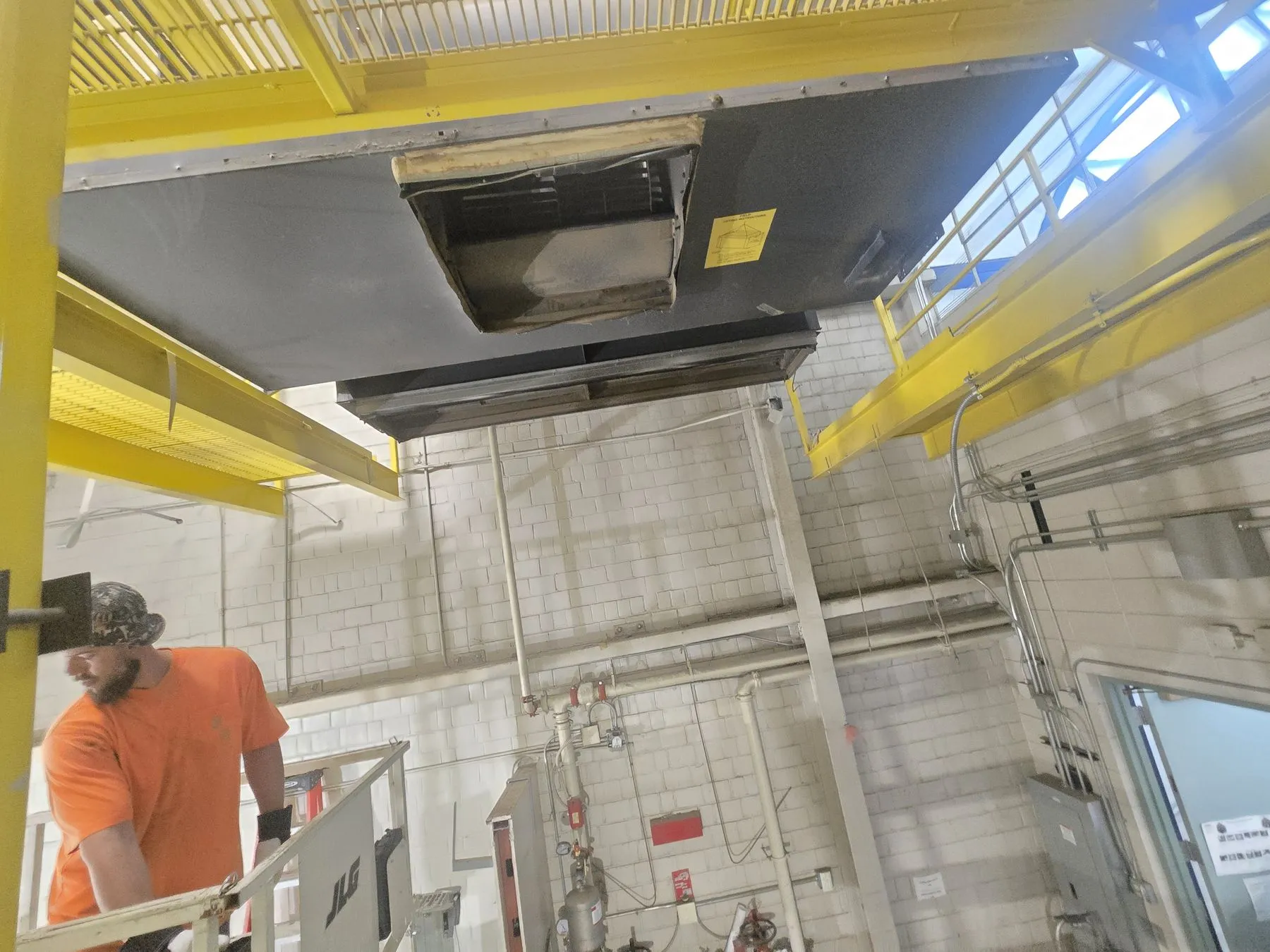 Large air handling unit mounted 35 feet up near the ceiling of a campus mechanical space