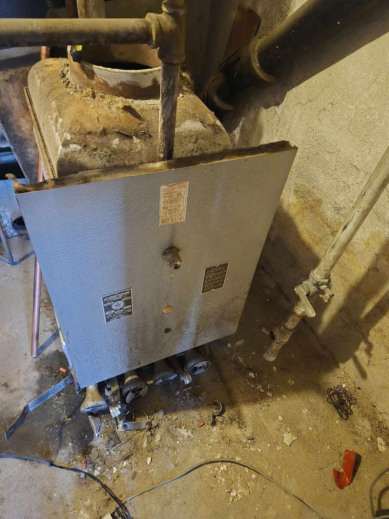 Old residential boiler in a tight basement utility corner before removal