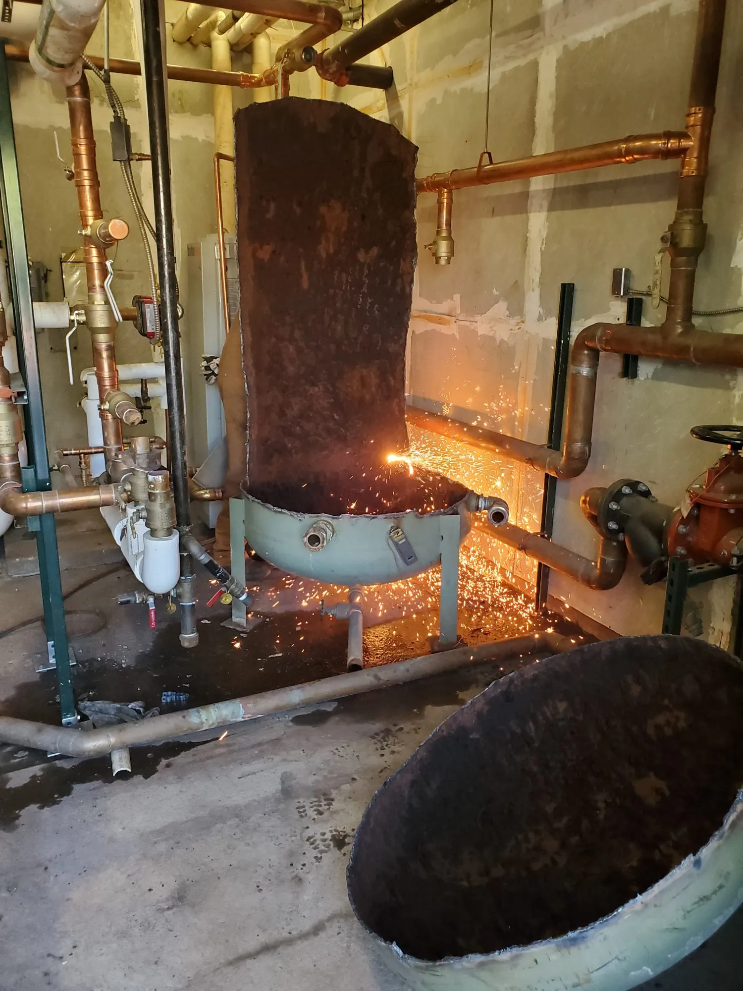 Torch cutting a steel tank with sparks flying