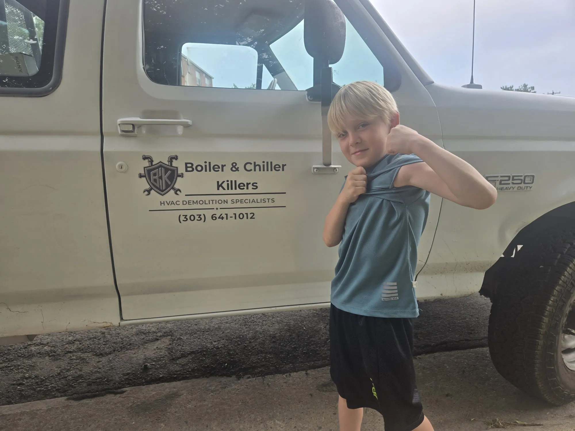 A young family member flexing in front of the BCK work truck door